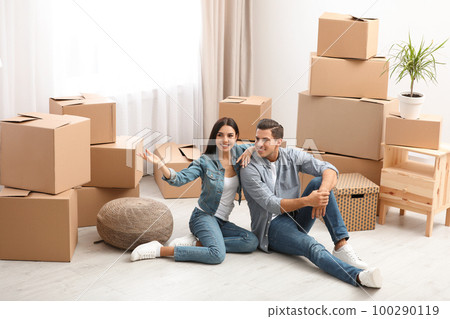 Happy couple in room with cardboard boxes on moving day Happy couple in room with cardboard boxes on moving day 100290119