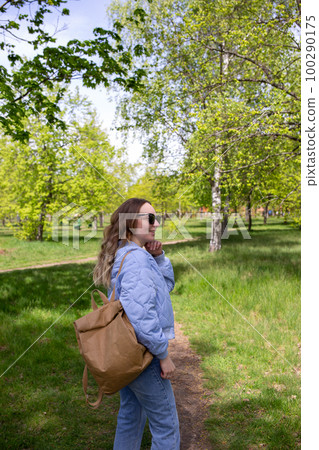 A young girl walks alone in the park with a backpack A young girl walks alone in the park with a backpack 100290175
