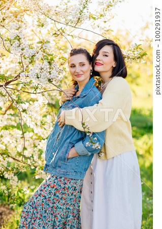 two attractive women hugging in a spring garden.  100291937