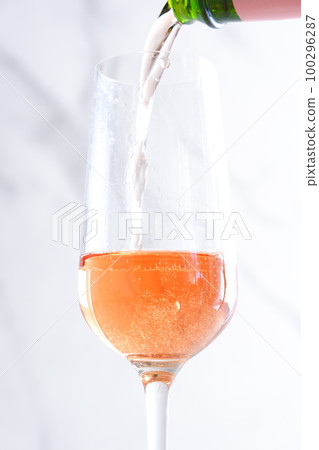 Pour well-chilled rosé champagne (sparkling wine) into a flute glass Pour well-chilled rosé champagne (sparkling wine) into a flute glass 100296287