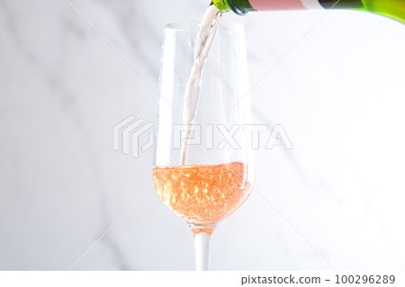 Pour well-chilled rosé champagne (sparkling wine) into a flute glass 100296289