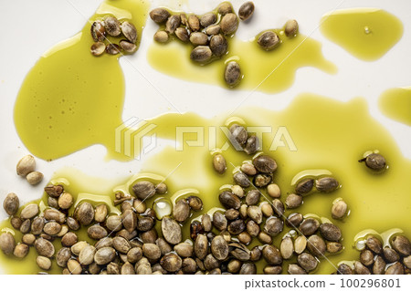 dry hemp seeds and a splash of hemp oil on a white plate, superfood and healthy eating concept 100296801