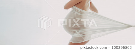 Pregnant woman maternity artistic photoshoot. Pregnancy profile portrait showing beautiful big belly baby bump in third trimester. Woman expecting baby shot in profile in panoranmic banner image 100296863