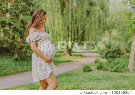 Portrait of pregnant woman holding belly baby bump happy and smilling of happiness in 3rd trimester in spring forest nature. Asian expectant mother holding tummy. Healthy pregnancy concept Portrait of pregnant woman holding belly baby bump happy and smilling of happiness in 3rd trimester in spring forest nature. Asian expectant mother holding tummy. Healthy pregnancy concept 100296864