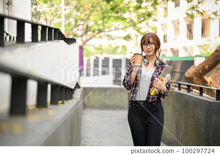 Pretty Asian female college student in casual clothes walking along the campus building 100297724