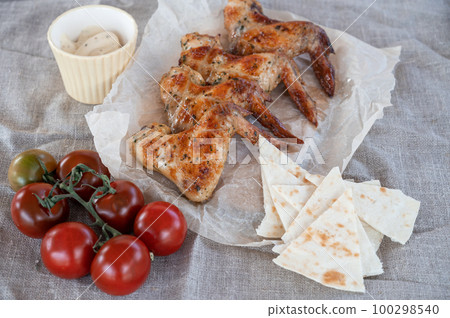 Ready spicy grilled chicken wings with greens and tomato 100298540