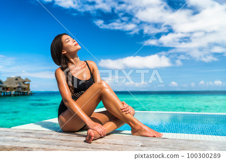 Luxury Bora Bora vacation hotel woman sunbathing relaxing at overwater bungalow suite in Tahiti resort, French Polynesia travel destination Luxury Bora Bora vacation hotel woman sunbathing relaxing at overwater bungalow suite in Tahiti resort, French Polynesia travel destination 100300289