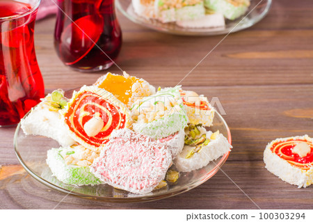 Traditional Turkish Delight. on a saucer and karkade in cups on a wooden table Traditional Turkish Delight. on a saucer and karkade in cups on a wooden table 100303294