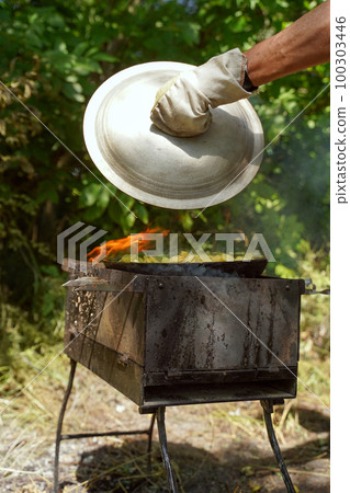 Meat on an open fire, delicious meat on a picnic. Fried potatoes in the forest. Lifestyle. Vertical orientation Meat on an open fire, delicious meat on a picnic. Fried potatoes in the forest. Lifestyle. Vertical orientation 100303446