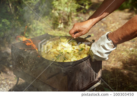 BBQ picnic. Relax on the campsite, cooking juicy fried potatoes BBQ picnic. Relax on the campsite, cooking juicy fried potatoes 100303450