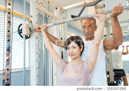 在健身房進行肌肉訓練的中年婦女和教練員 100303568
