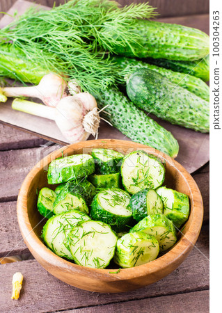 Freshly salted cucumber pickled with garlic and dill in a wooden plate. Rustic style Freshly salted cucumber pickled with garlic and dill in a wooden plate. Rustic style 100304263