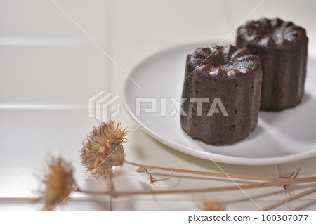 瓷磚桌上的白色盤子上的 Canelé 瓷磚桌上的白色盤子上的 Canelé 100307077