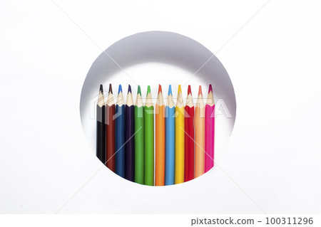 A set of colored pencils peek out of a circle on a white background. Sharpened pencils concept 100311296