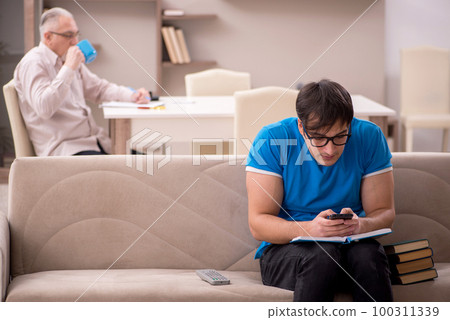 Young male student and his grandfather at home Young male student and his grandfather at home 100311339
