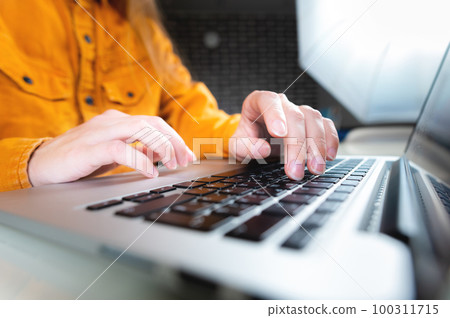 Fingers are typing on a computer keyboard, close-up. Close focus of a set of female hands. A man working in a home office keeps his hand on the keyboard close-up 100311715
