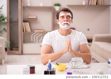 Young man shaving face at home 100312352