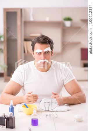Young man shaving face at home 100312354