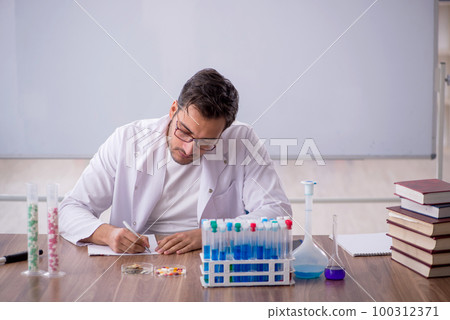 Young male chemist in front of white board 100312371