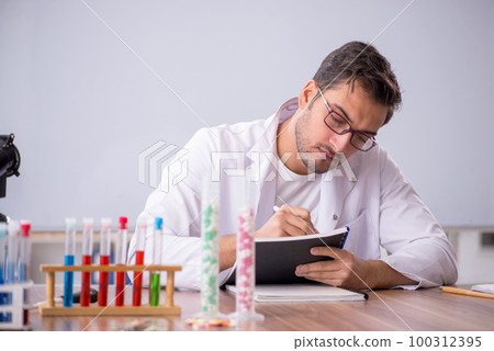 Young male chemist in front of white board 100312395