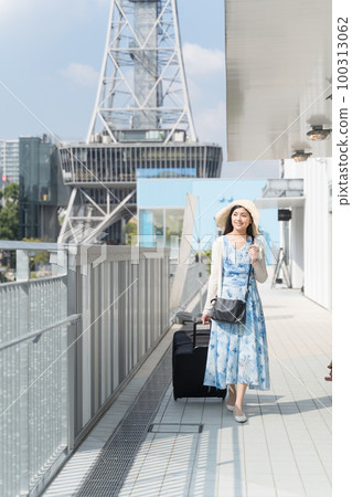 A young woman pulling a suitcase and sightseeing in Nagoya 100313062