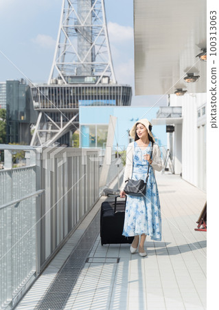 A young woman pulling a suitcase and sightseeing in Nagoya 100313063