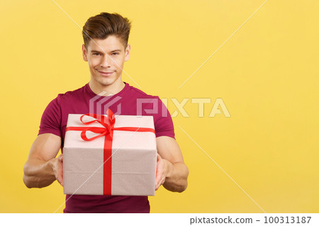Happy man looking at the camera giving a present Happy man looking at the camera giving a present 100313187