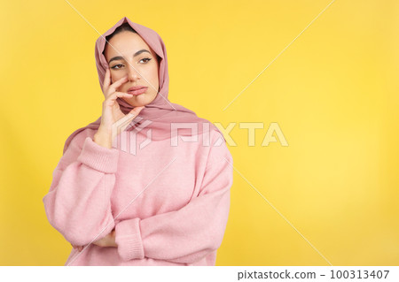 Bored muslim woman standing and looking away Bored muslim woman standing and looking away 100313407