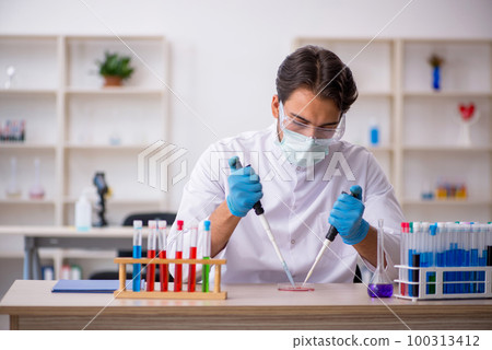 Young male chemist working at the lab 100313412