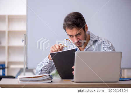Young male teacher sitting in the classroom 100314504