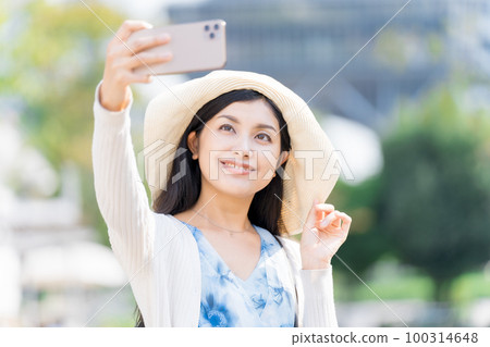 A young woman taking a commemorative photo with a smartphone 100314648