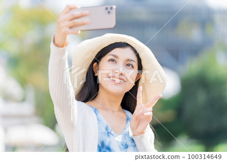 A young woman taking a commemorative photo with a smartphone 100314649
