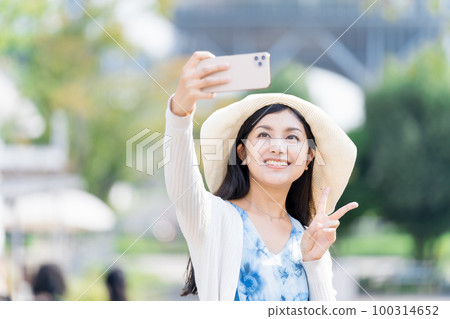 A young woman taking a commemorative photo with a smartphone A young woman taking a commemorative photo with a smartphone 100314652