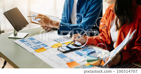 UX developer and ui designer brainstorming about mobile app interface wireframe design with customer breif and color code at office.. UX developer and ui designer brainstorming about mobile app interface wireframe design with customer breif and color code at office.. 100314707