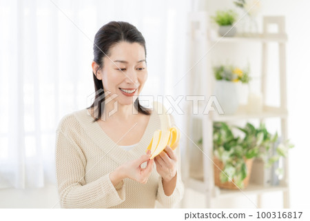 一個中年婦女手裡拿著香蕉剝皮 100316817