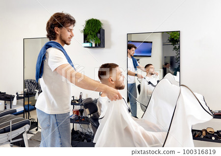Professional barber during work with man client 100316819