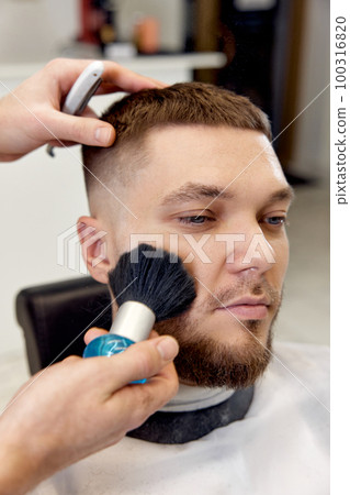 Hairstylist serving handsome man in barber shop. 100316820