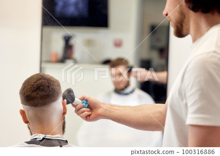 barber holding brush for talco in barber shop 100316886
