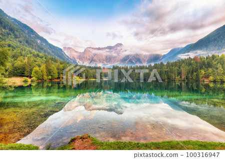Incredible view of sunset over Fusine lake with Mangart peak on background. Incredible view of sunset over Fusine lake with Mangart peak on background. 100316947