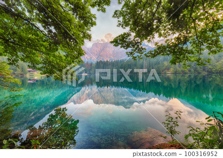 Incredible view of sunset over Fusine lake with Mangart peak on background. Incredible view of sunset over Fusine lake with Mangart peak on background. 100316952