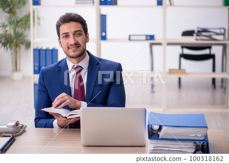 Young male employee reading book at workplace Young male employee reading book at workplace 100318162