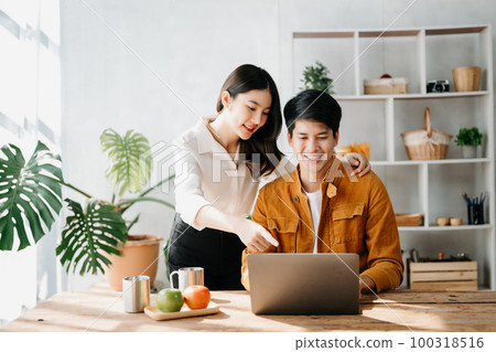 Two Asian business workers talking on the smartphone and using laptop at the home office. 100318516