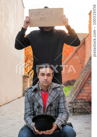Two men with a sign saying forgive me outdoors Two men with a sign saying forgive me outdoors 100319356