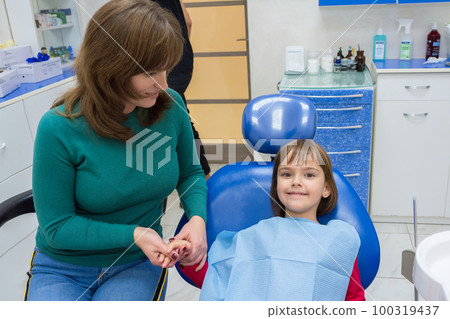 A mother with her daughter at the dentists. The mother is holding her daughter on her hand 100319437