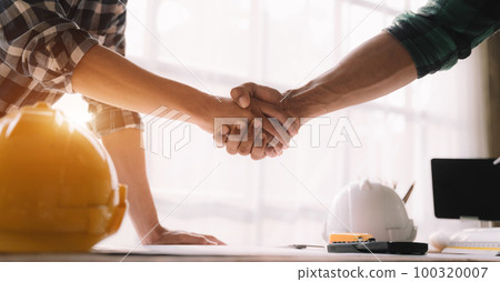 Construction workers, architects and engineers shake hands while working for teamwork and cooperation after completing an agreement in an office facility, successful cooperation concept. 100320007