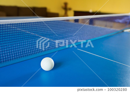A tennis white ball for Ping-Pong on a blue table. A Ping-Pong game. Sport games A tennis white ball for Ping-Pong on a blue table. A Ping-Pong game. Sport games 100320280