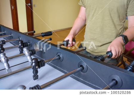 A Detail of a boy hand, playing table tennis. A football table. Sports A Detail of a boy hand, playing table tennis. A football table. Sports 100320286