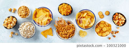 Salty snacks, party mix, overhead flat lay panorama. An assortment of appetizers 100321000