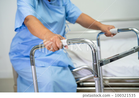 Asian lady patient use walker in hospital to support walking. Asian lady patient use walker in hospital to support walking. 100321535