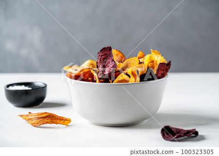 Healthy vegetable chips in a bowl, marine salt over light surface with grey concrete background 100323305